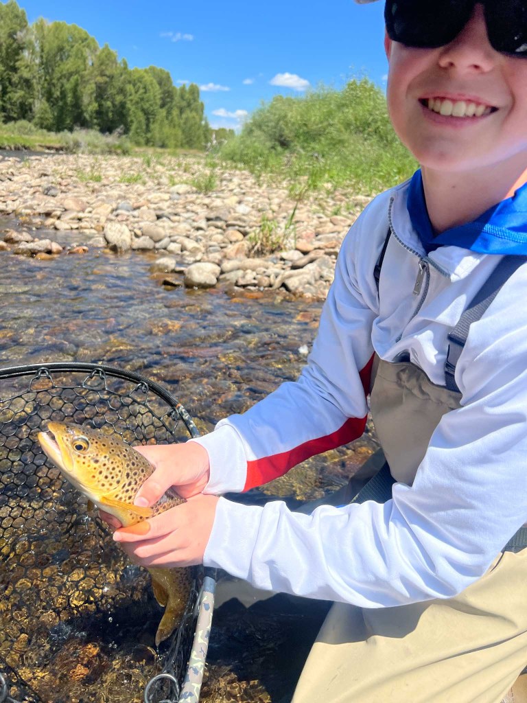 A kid celebrating catching a brown trout east river crested butte