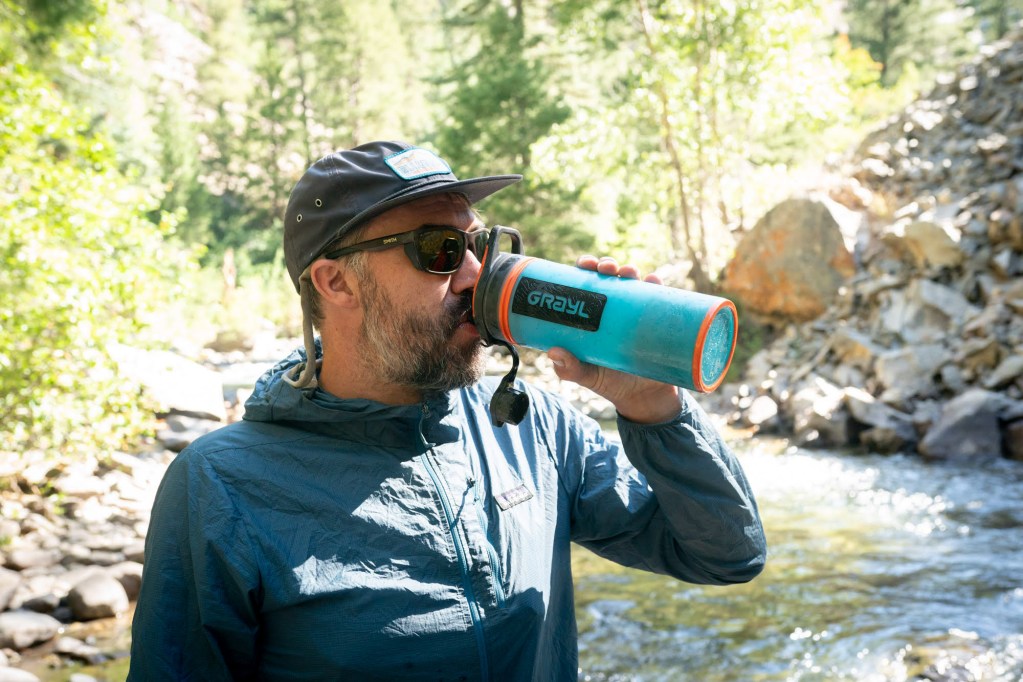 Angler drinking from Grayl Water Bottle in Patagonia Houdini Rain Jacket
