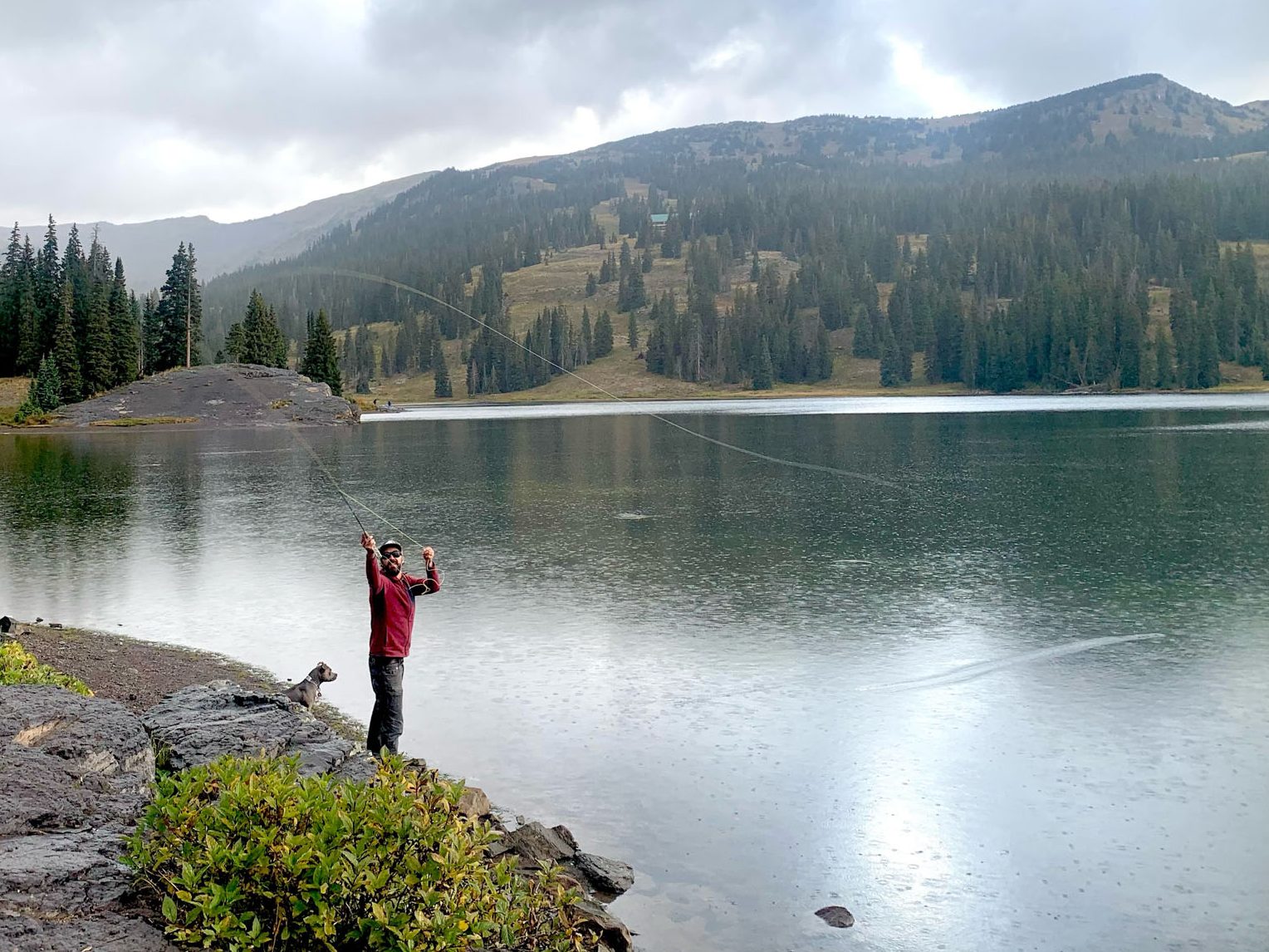 Man and dog fly fishing Lake Irwin Crested Butte. 